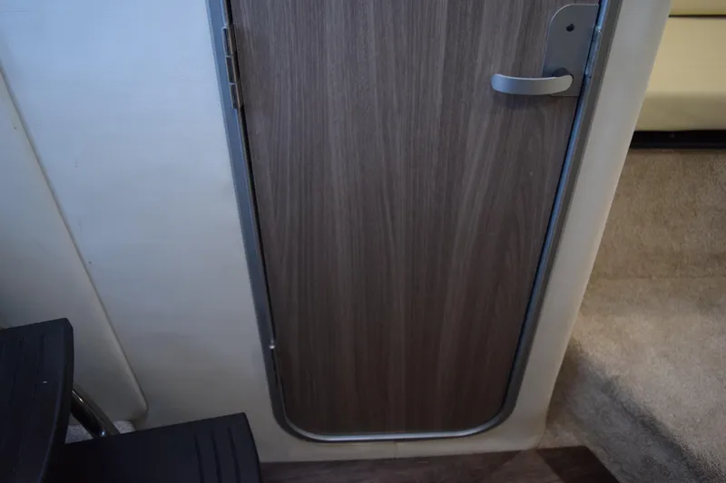 Slide: The Image of Interior cabin door of 2021 Regal 26 XO boat, featuring wood finish and modern handle. - 141