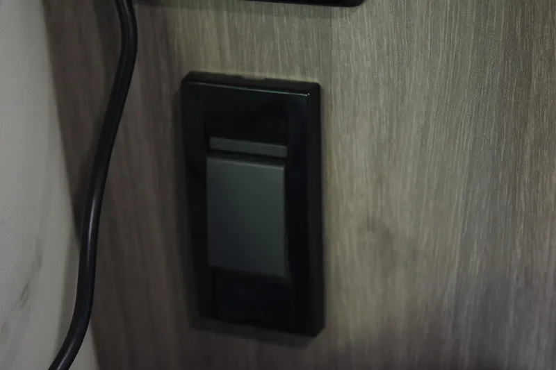 Slide: The Image of Light switch on a wooden panel in a 2021 Regal 26 XO boat interior. - 170