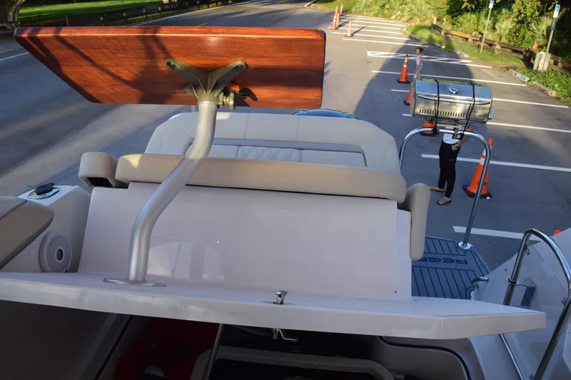 Slide: The Image of 2021 Regal 26 XO boat with seating and grill setup in a parking area. - 185