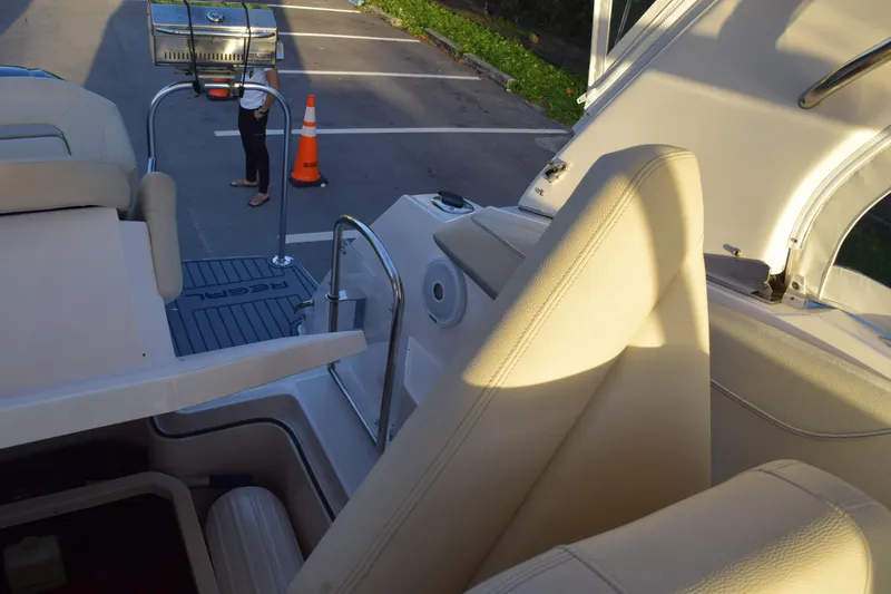 Slide: The Image of 2021 Regal 26 XO boat interior with beige seating, docked near parking area. - 186