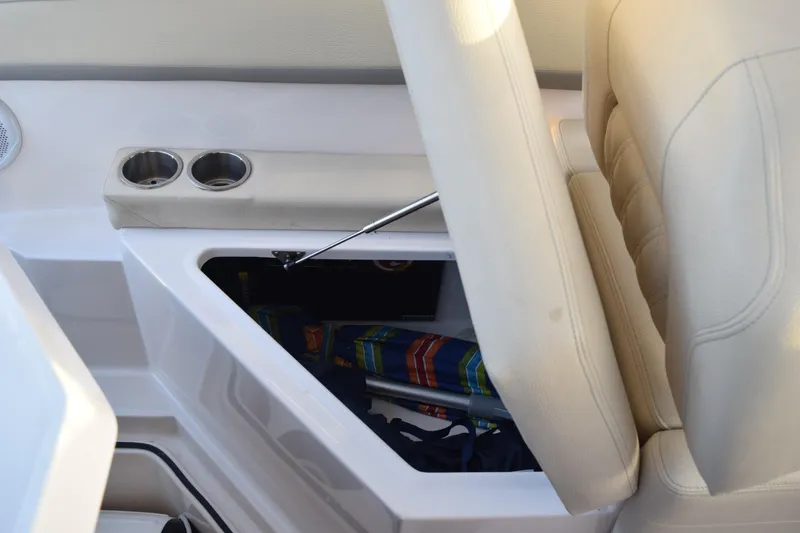 Slide: The Image of 2021 Regal 26 XO boat interior storage compartment with cup holders and beige seating. - 200