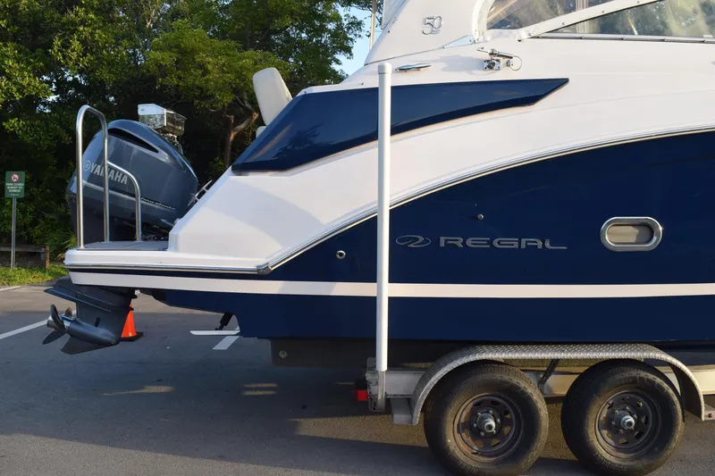 Slide: The Image of 2021 Regal 26 XO boat on trailer with Yamaha outboard motor, parked outdoors. - 225