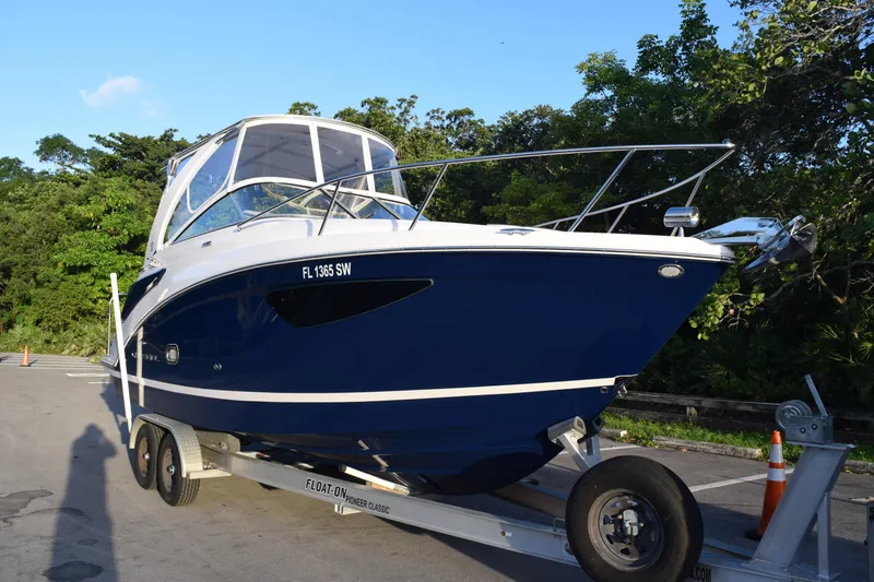 Slide: The Image of 2021 Regal 26 XO boat on trailer, sleek design, blue hull, parked outdoors. - 229