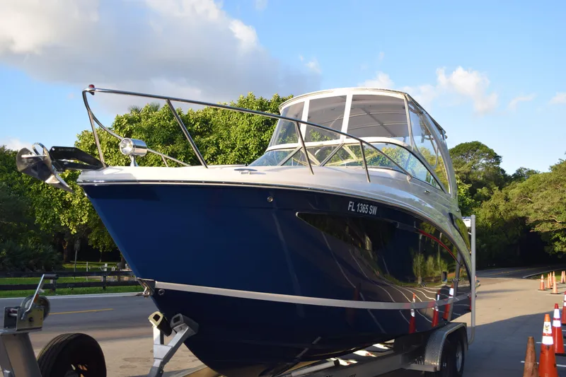 Slide: The Image of 2021 Regal 26 XO boat on trailer, parked on a sunny road. - 231