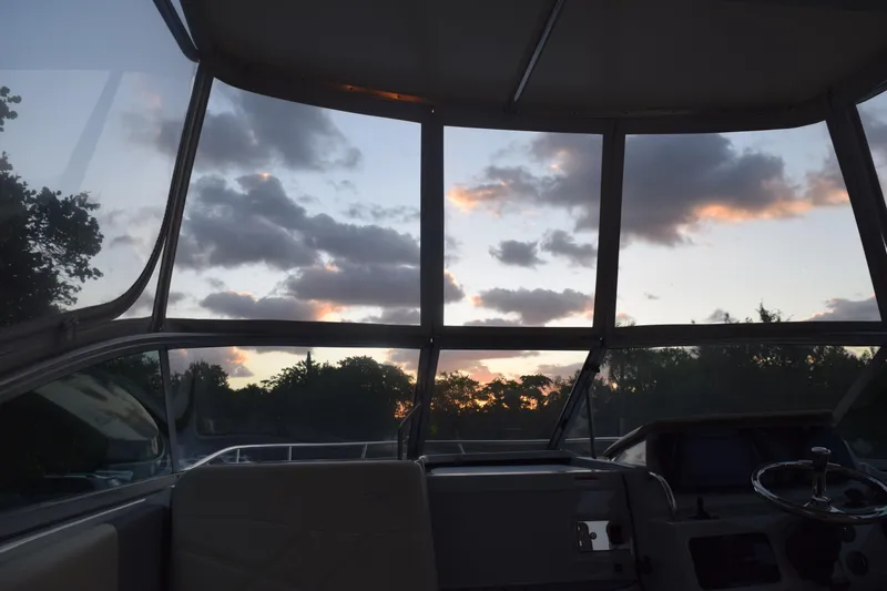 Slide: The Image of Interior view of 2021 Regal 26 XO boat at sunset, showcasing helm and windows. - 80