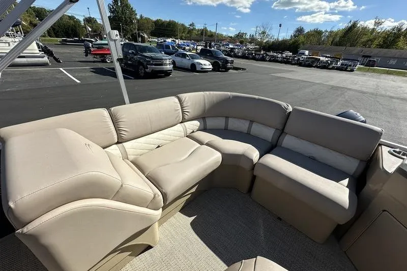 Slide: The Image of 2014 Bennington 24 SPDX boat with beige seating, parked in a lot under a clear sky. - 12