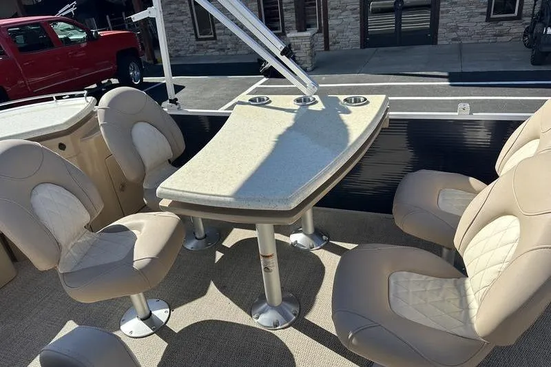 Slide: The Image of 2014 Bennington 24 SPDX boat interior with beige seating and table setup. - 18