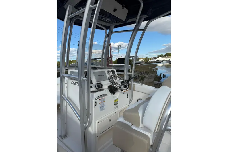 Slide: The Image of 2018 Robalo R222 Explorer boat cockpit with steering wheel and controls, dockside view. - 4