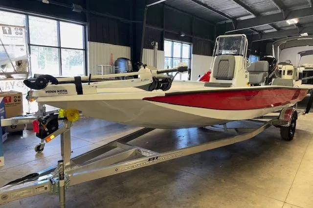 Slide: The Image of 2026 Xpress H22B Bay boat in showroom, featuring red and white design on trailer. - 14