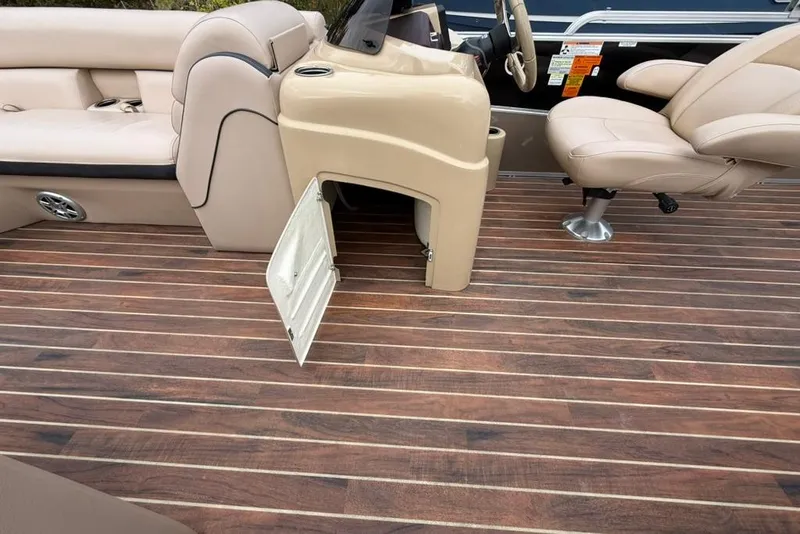 Slide: The Image of 2016 Berkshire 230CL STS boat interior with open storage, beige seating, and wood-style flooring. - 12