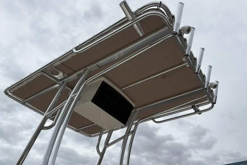 Slide: The Image of 2026 Pioneer Islander 180 boat T-top with rod holders against cloudy sky. - 12