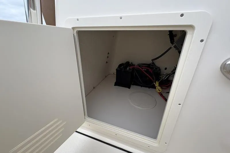 Slide: The Image of Open storage compartment on 2026 Pioneer Islander 180 boat, showing battery and wiring. - 22