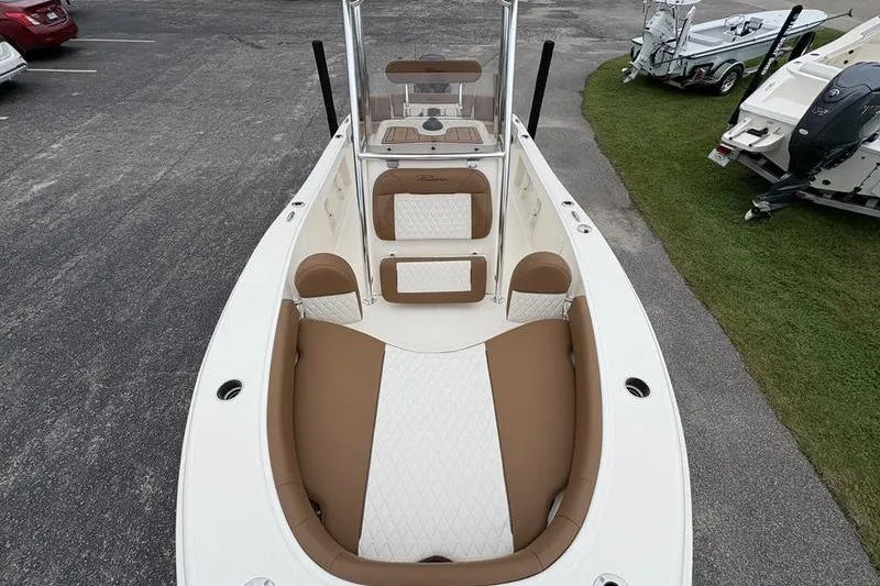 Slide: The Image of 2026 Pioneer Islander 180 boat interior with tan and white seating, parked on pavement. - 27