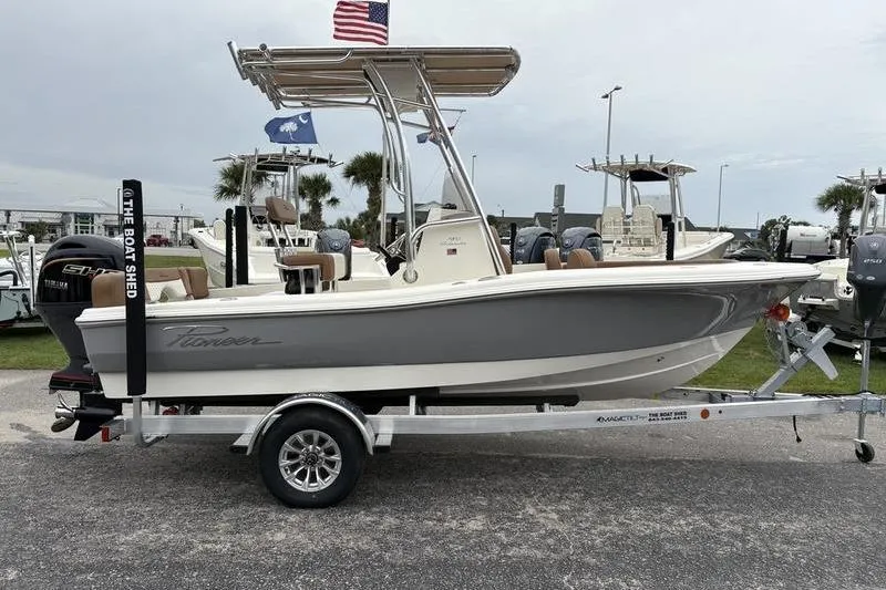 Slide: The Image of 2026 Pioneer Islander 180 boat on trailer, displayed outdoors with flags. - 5