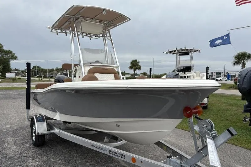 Slide: The Image of 2026 Pioneer Islander 180 boat on trailer, parked outdoors with flags in background. - 6