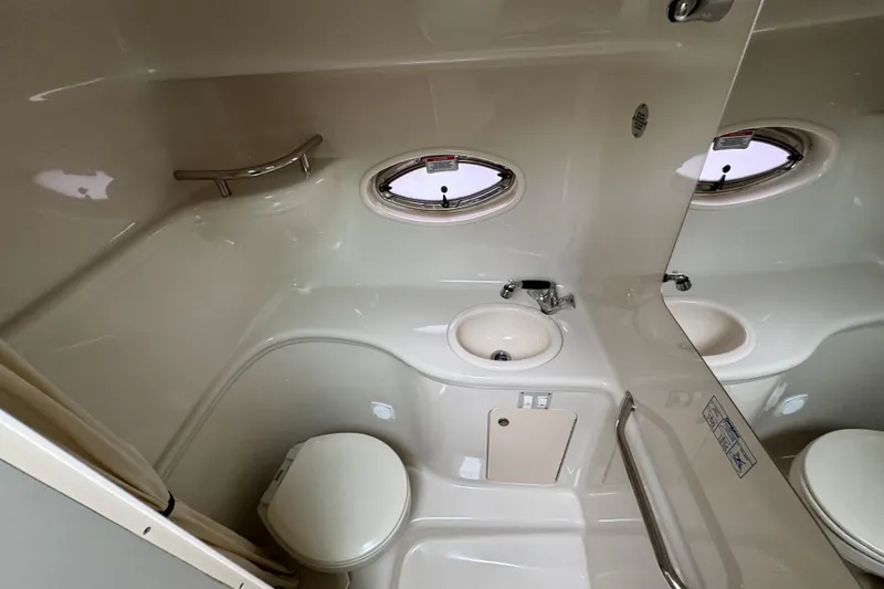 Slide: The Image of 2007 Sea Ray 290 Amberjack bathroom with sink, toilet, and porthole window. - 23