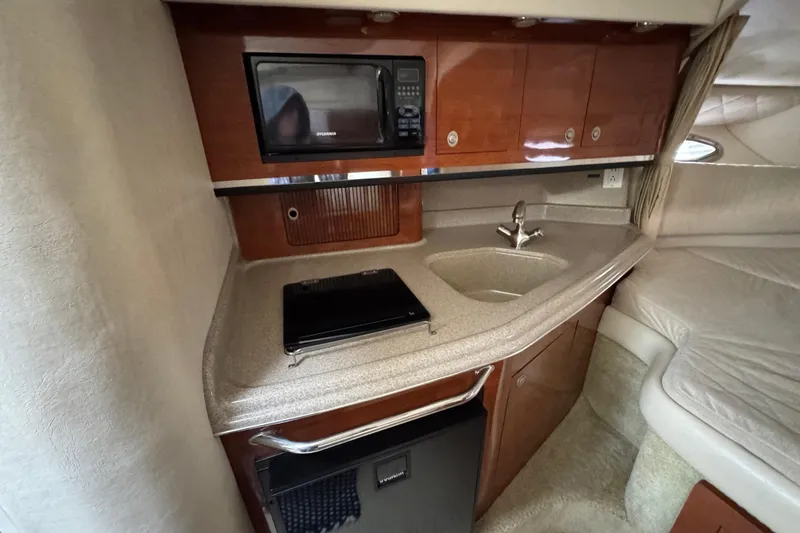 Slide: The Image of 2007 Sea Ray 290 Amberjack cabin with kitchenette, featuring microwave, sink, and compact fridge. - 26