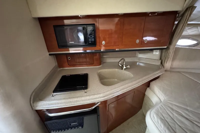 Slide: The Image of 2007 Sea Ray 290 Amberjack cabin with kitchenette, featuring sink, microwave, and compact fridge. - 29