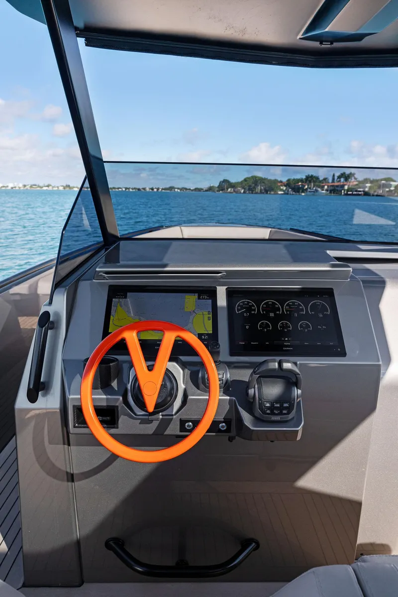 Slide: The Image of Cockpit of 2022 Vanquish Yachts VQ40 with modern controls and vibrant orange steering wheel. - 40