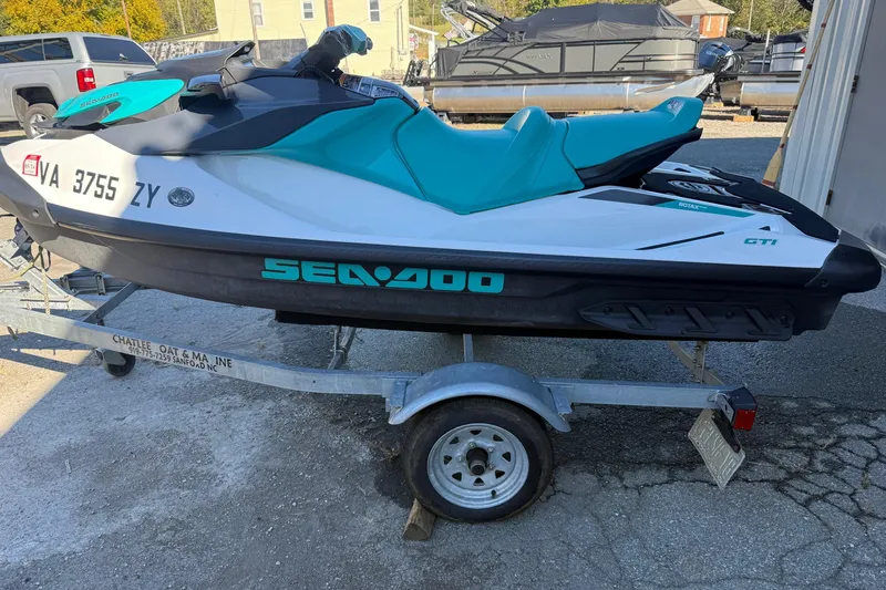 The Image of 2021 Seadoo GTI90 jet ski on trailer, teal and white design, parked outdoors. - 1