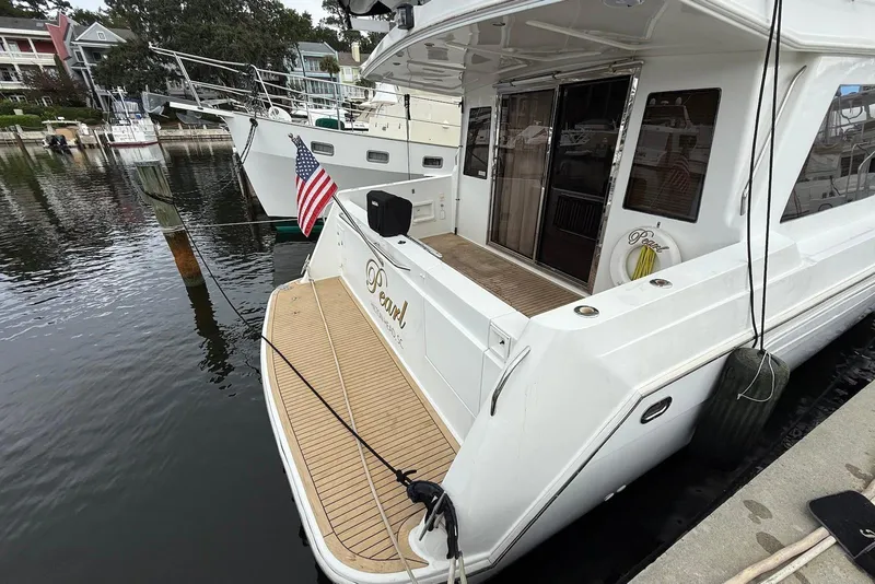 Slide: The Image of 2004 Navigator 4800 yacht docked, featuring a spacious deck and American flag. - 19