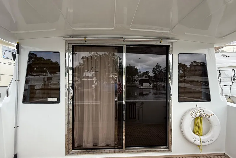 Slide: The Image of 2004 Navigator 4800 yacht with sliding glass doors and life preserver labeled "Pearl." - 22