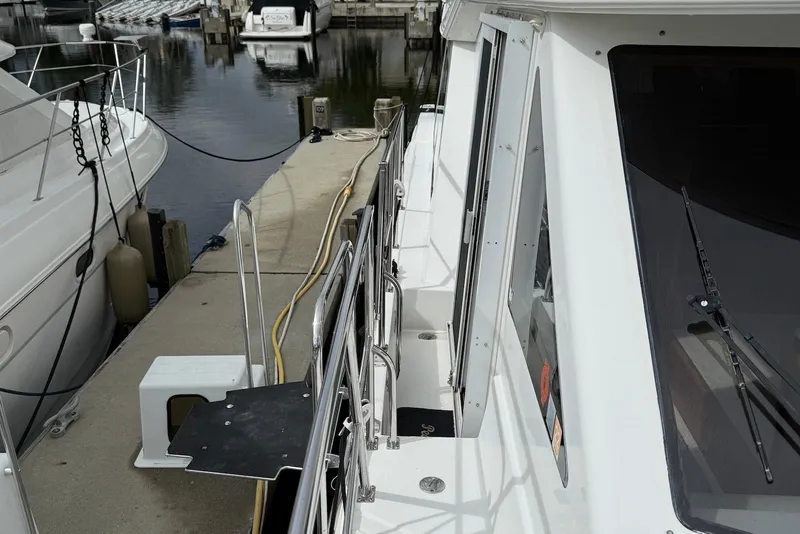 Slide: The Image of 2004 Navigator 4800 yacht docked at marina, side view with railing and walkway. - 26