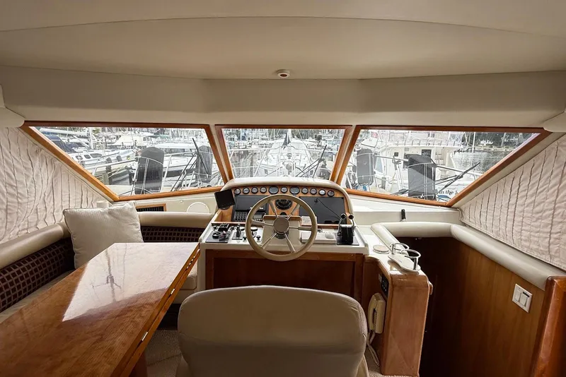 Slide: The Image of Interior view of 2004 Navigator 4800 yacht helm with wooden accents and marina backdrop. - 32