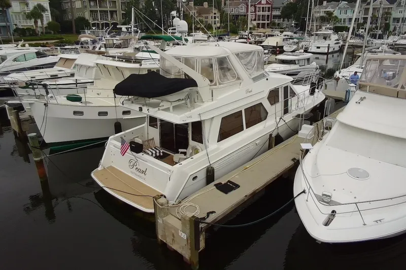 Slide: The Image of 2004 Navigator 4800 yacht docked in a marina, surrounded by other boats. - 4