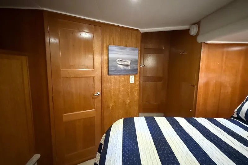 Slide: The Image of Wood-paneled bedroom interior of 2004 Navigator 4800 yacht with striped bedding and wall art. - 44
