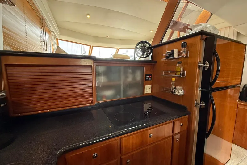 Slide: The Image of 2004 Navigator 4800 yacht kitchen with wooden cabinets, stovetop, and refrigerator. - 62