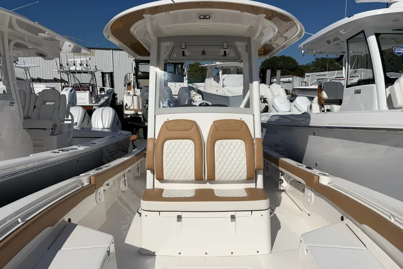 Slide: The Image of 2025 Regulator 26XO boat interior with tan and white seating, docked among other boats. - 21