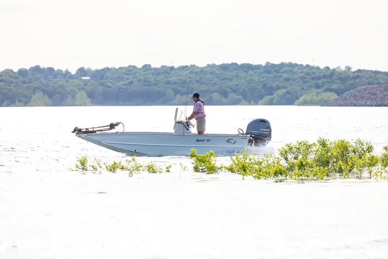 Slide: The Image of Man navigating G3 Bay 17 boat on a serene lake, 2026 model. - 5