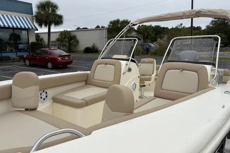 Slide: The Image of 2026 Scout 195 Sport Dorado boat with beige seating and windshield in a parking lot. - 21