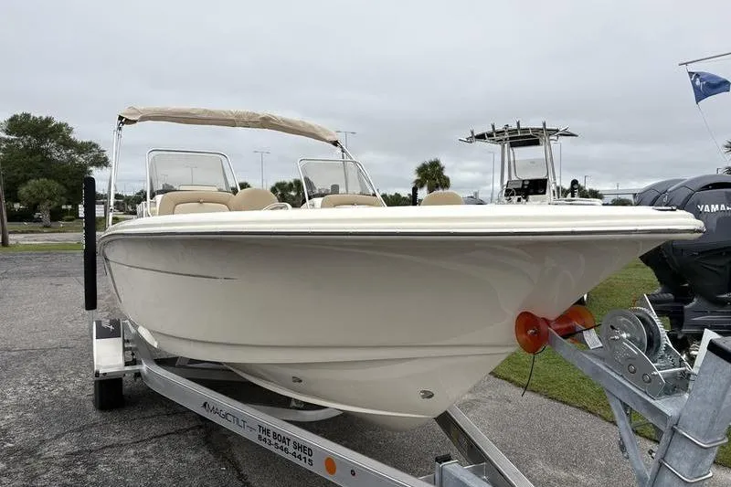 Slide: The Image of 2026 Scout 195 Sport Dorado boat on trailer, displayed outdoors with flags in background. - 6