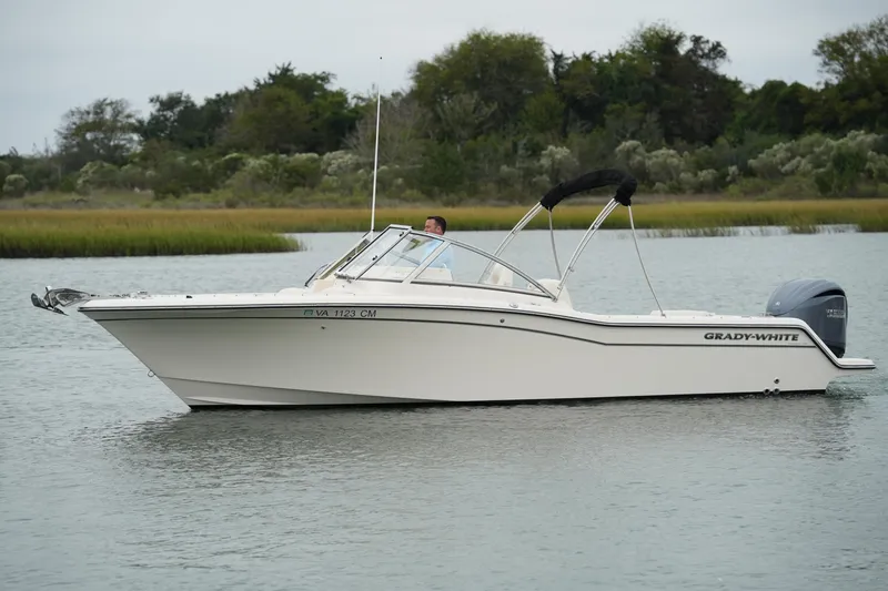 The Image of 2022 Grady-White Freedom 235 boat on calm water, surrounded by lush greenery. - 0