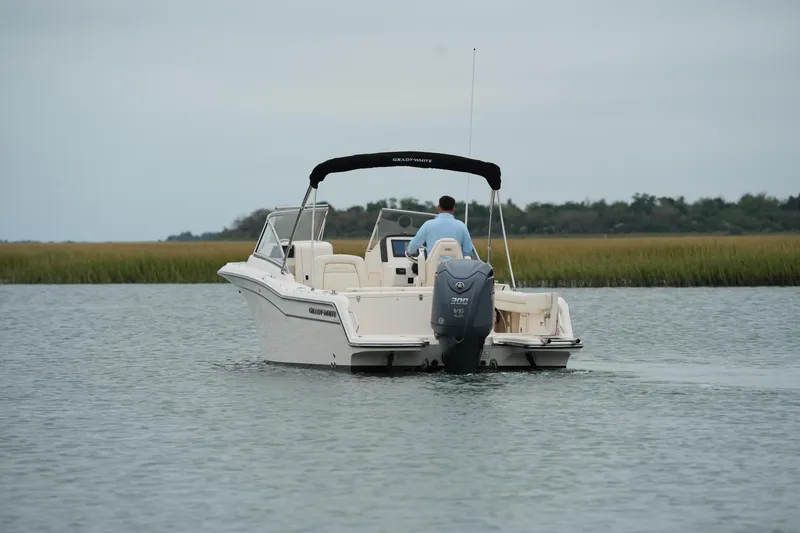 Slide: The Image of 2022 Grady-White Freedom 235 boat cruising on calm water with lush greenery in the background. - 15