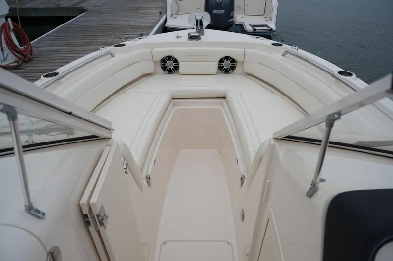 Slide: The Image of 2022 Grady-White Freedom 235 boat interior with seating and speakers, docked by the water. - 35