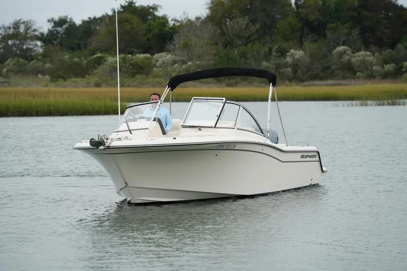 Slide: The Image of 2022 Grady-White Freedom 235 boat cruising on a calm lake with lush greenery. - 4