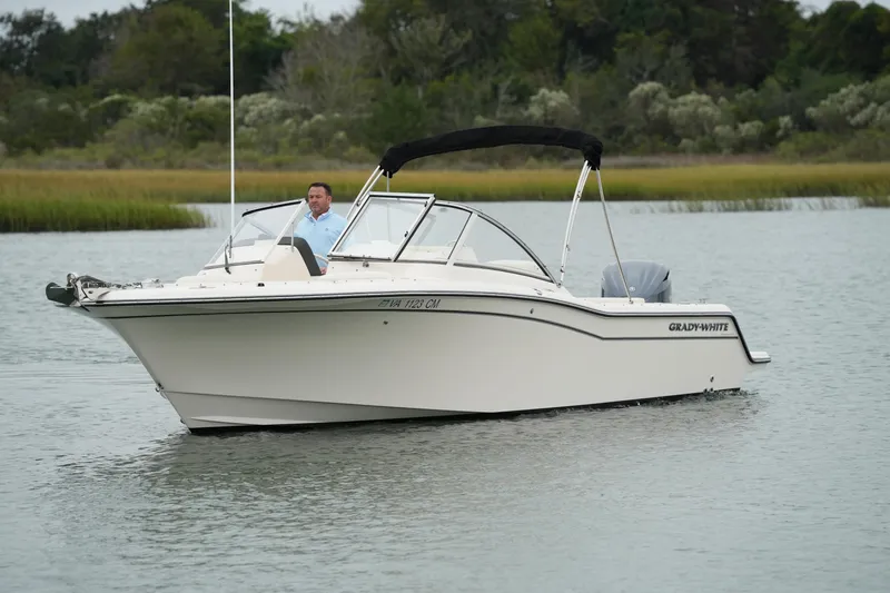 Slide: The Image of 2022 Grady-White Freedom 235 boat cruising on a calm lake with lush greenery. - 7