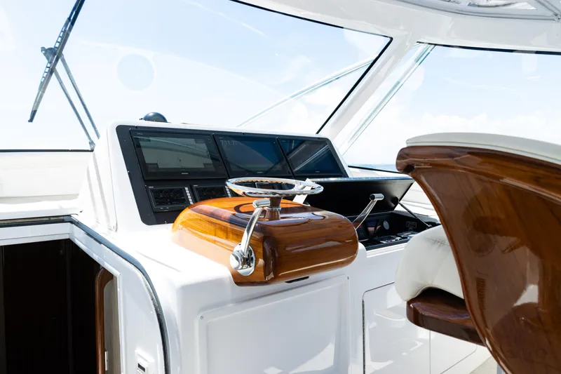 Slide: The Image of 2021 Viking 44 Open yacht helm with polished wood and modern navigation displays. - 58