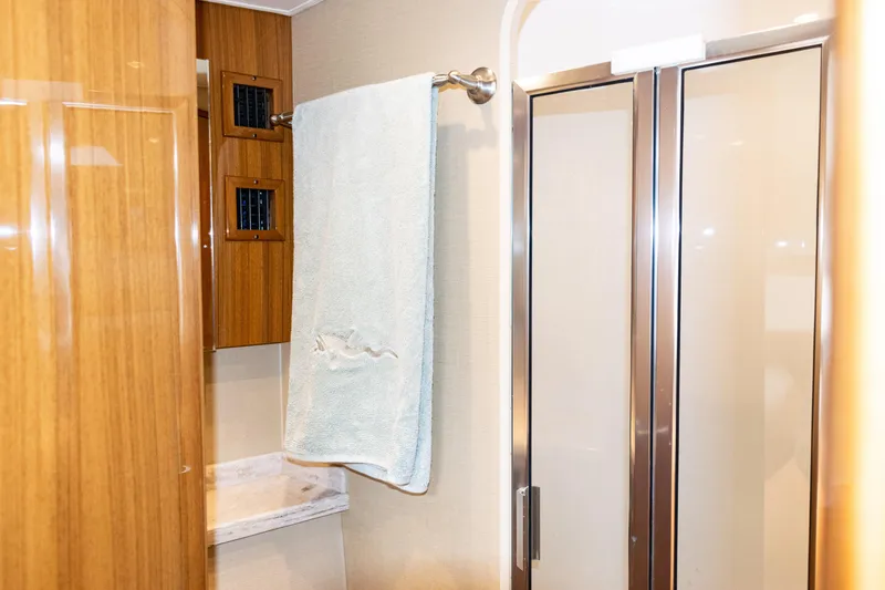 Slide: The Image of 2021 Viking 44 Open yacht bathroom with wooden cabinetry and glass shower doors. - 73