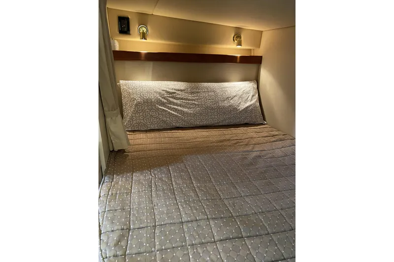 Slide: The Image of 2003 Cruisers Yachts 2870 Express cabin bed with patterned bedding and soft lighting. - 10