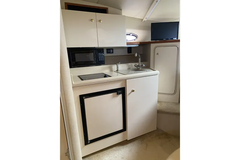 Slide: The Image of 2003 Cruisers Yachts 2870 Express interior kitchen with microwave, sink, and compact fridge. - 12