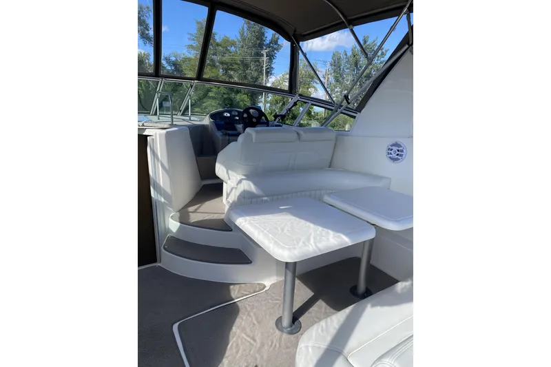 Slide: The Image of 2003 Cruisers Yachts 2870 Express interior with seating and helm, featuring white upholstery. - 5