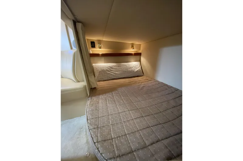 Slide: The Image of 2003 Cruisers Yachts 2870 Express cabin interior with cozy bed and ambient lighting. - 11