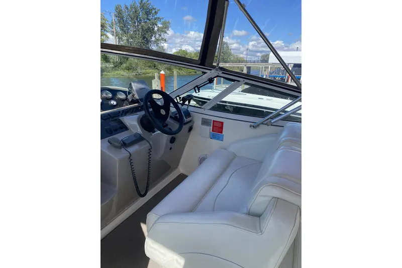 Slide: The Image of 2003 Cruisers Yachts 2870 Express helm with white seating and steering wheel. - 2