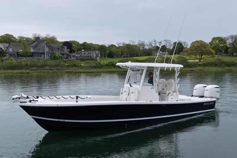 Slide: The Image of 2025 Regulator 30XO boat on calm water near waterfront homes. - 5