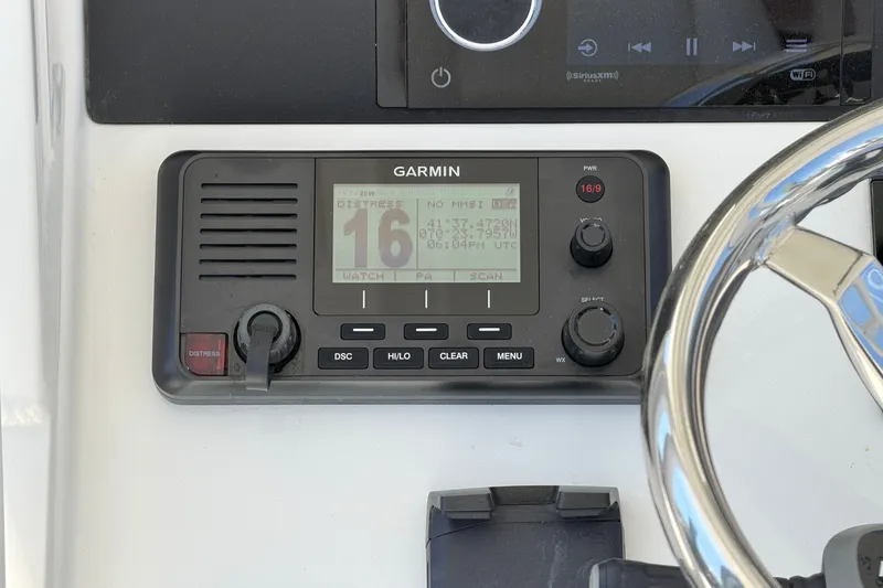 Slide: The Image of Garmin marine radio on 2025 Regulator 30XO boat dashboard, featuring distress button and controls. - 34