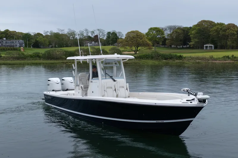 Slide: The Image of 2025 Regulator 30XO boat on calm water, featuring sleek design and dual engines. - 2